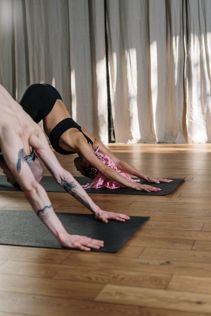 Two people practicing yoga indoors showcasing flexibility and fitness.