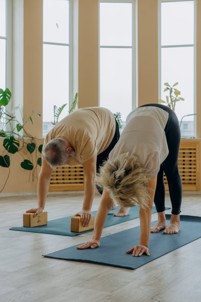 Senior couple engaging in a yoga session indoors with yoga bricks and mats, enhancing flexibility and wellness.